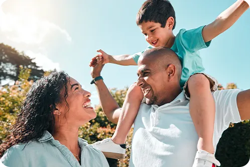 Parents and small child smiling at each other while child sits on father's shoulders