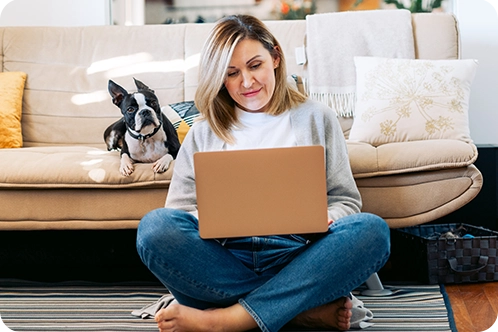 woman looking at computer with her dog