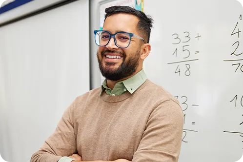 Male teacher smiling in front of white board with math problems