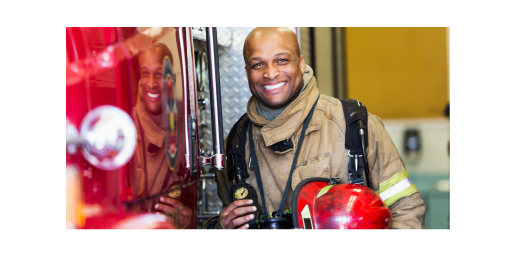 firefighter smiling in uniform next to fire truck