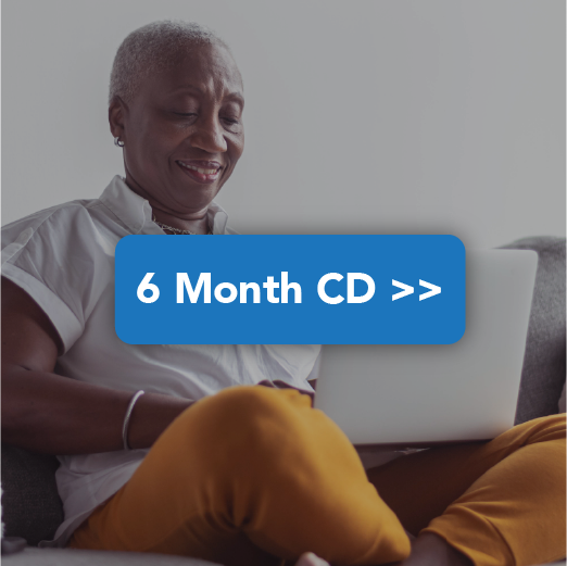 Black woman smiling while looking at CD offers online while at home on the couch