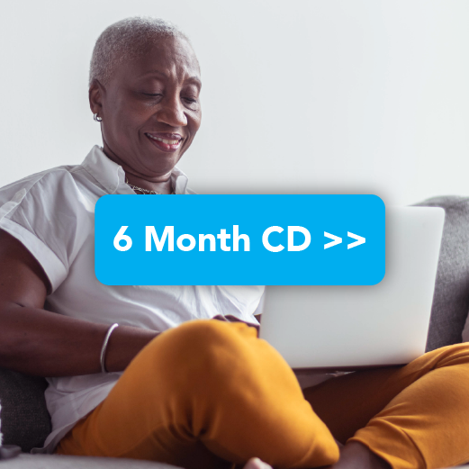 Black woman smiling while looking at CD offers online while at home on the couch