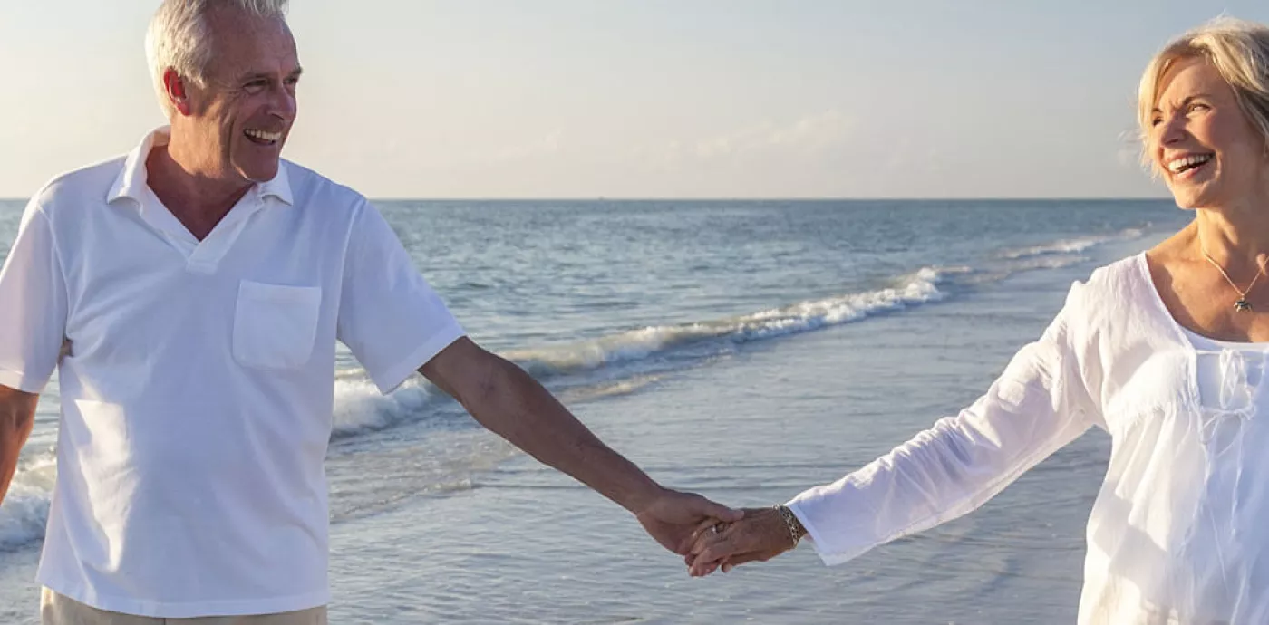 Senior couple holding hands and laughing on the beach