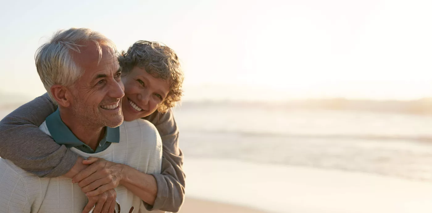 Senior couple smiling and playing on the beach