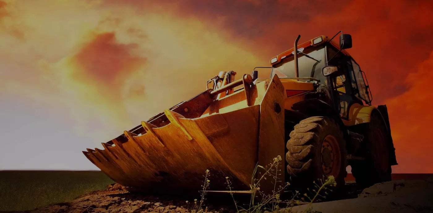 close up image of construction equipment with an orange sky behind it