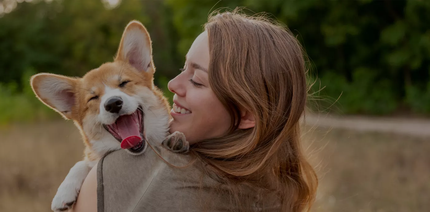 woman holding dog while both are smiling