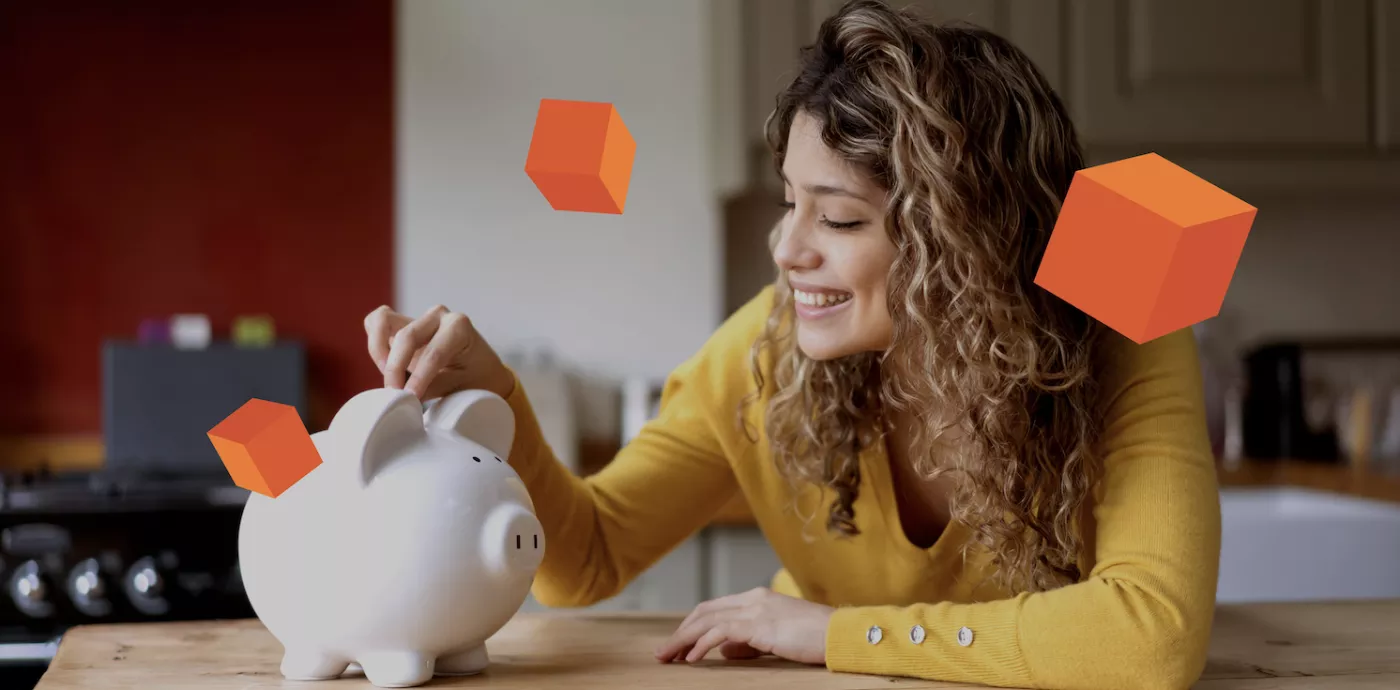 woman smiling as she fills her piggy bank