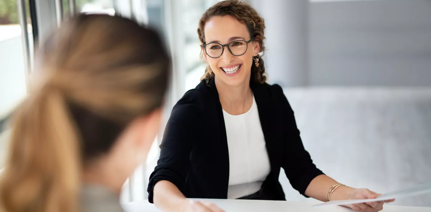 business women smiling while talking with colleague 