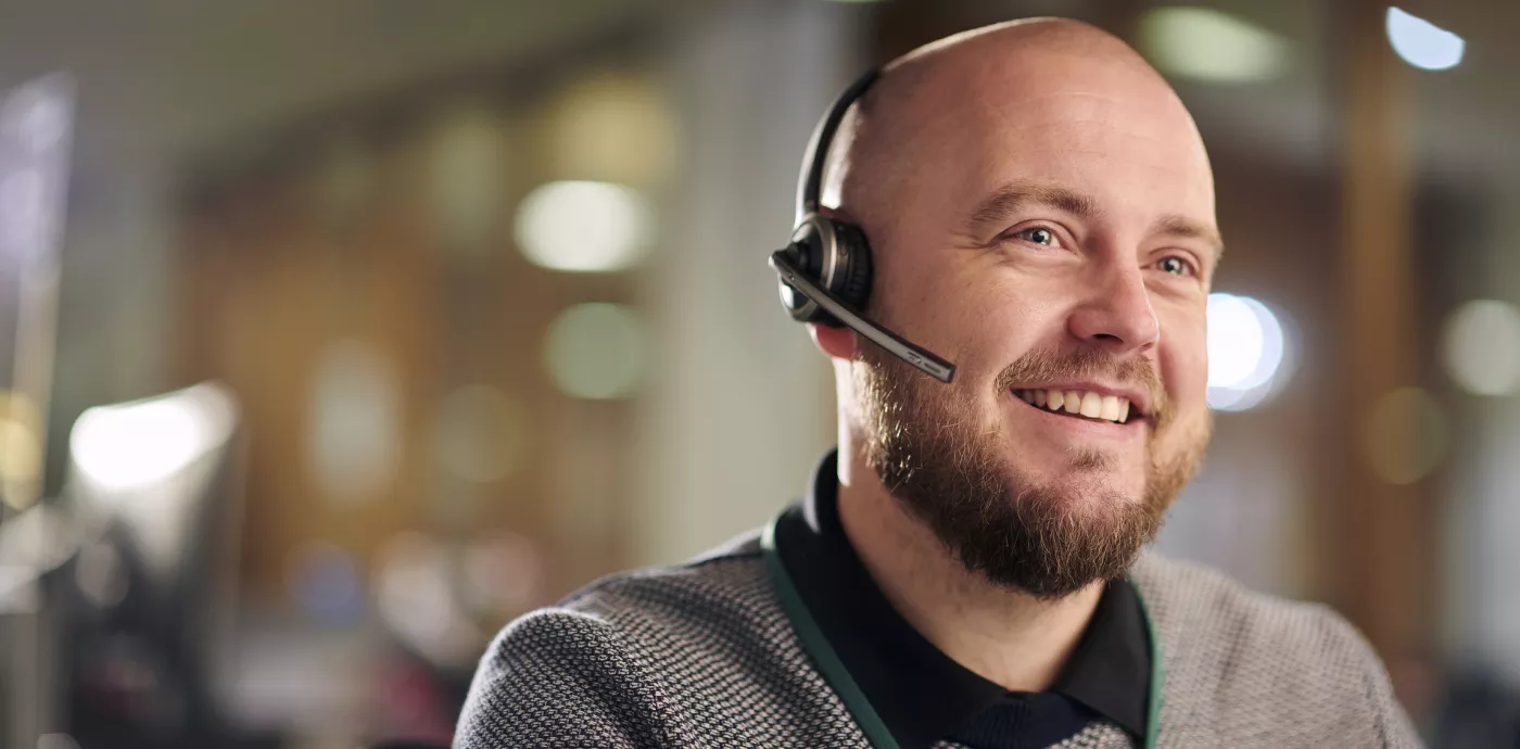 man smiling as he talks with customer over his headset