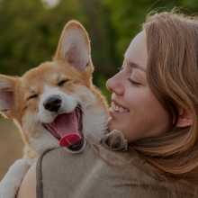 woman holding dog while both are smiling
