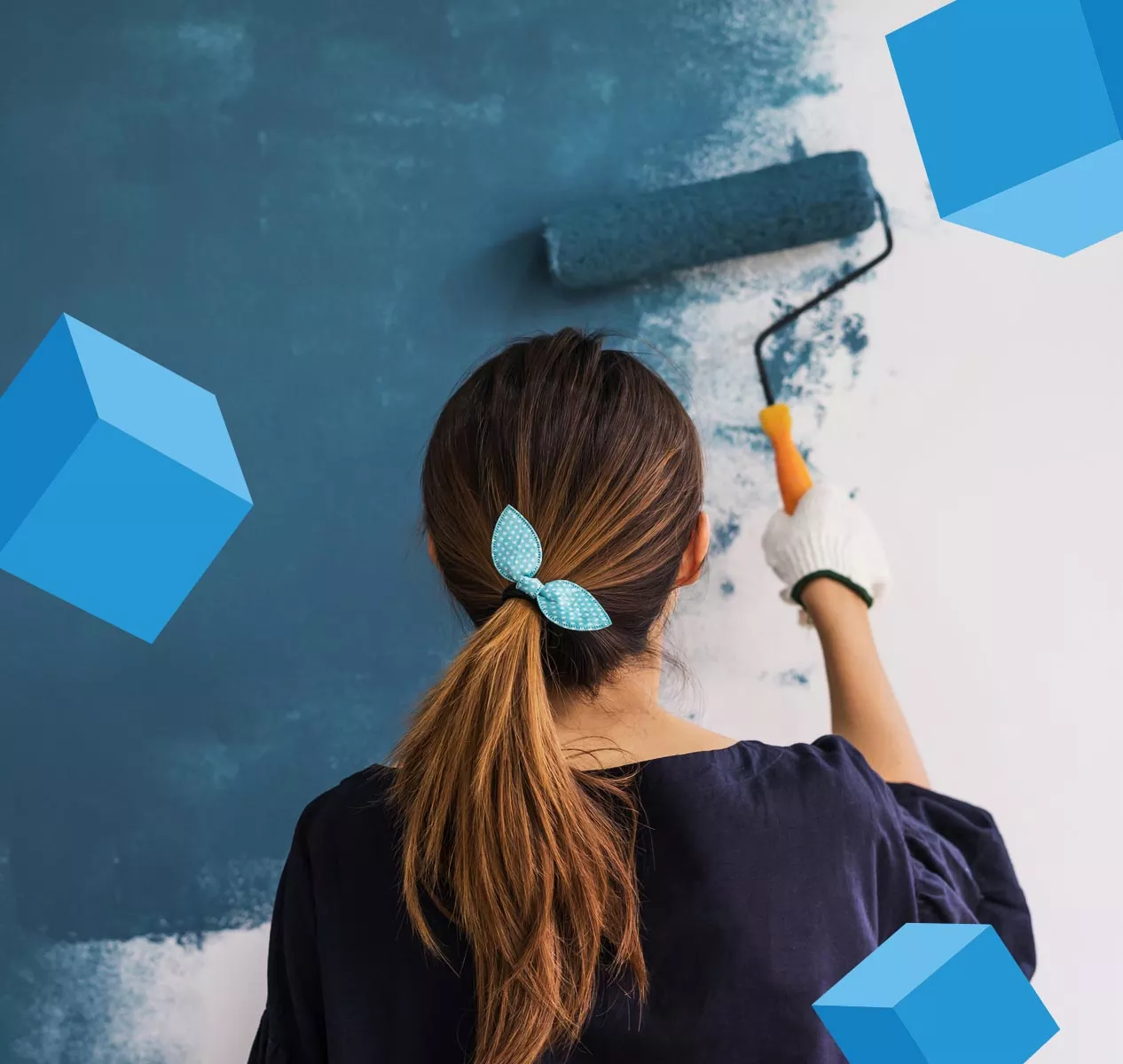 woman painting wall with blue cubes floating around her
