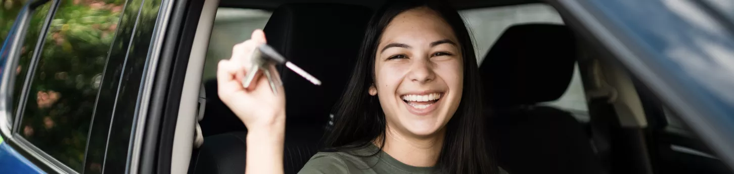 woman holding keys to her new car and smiling