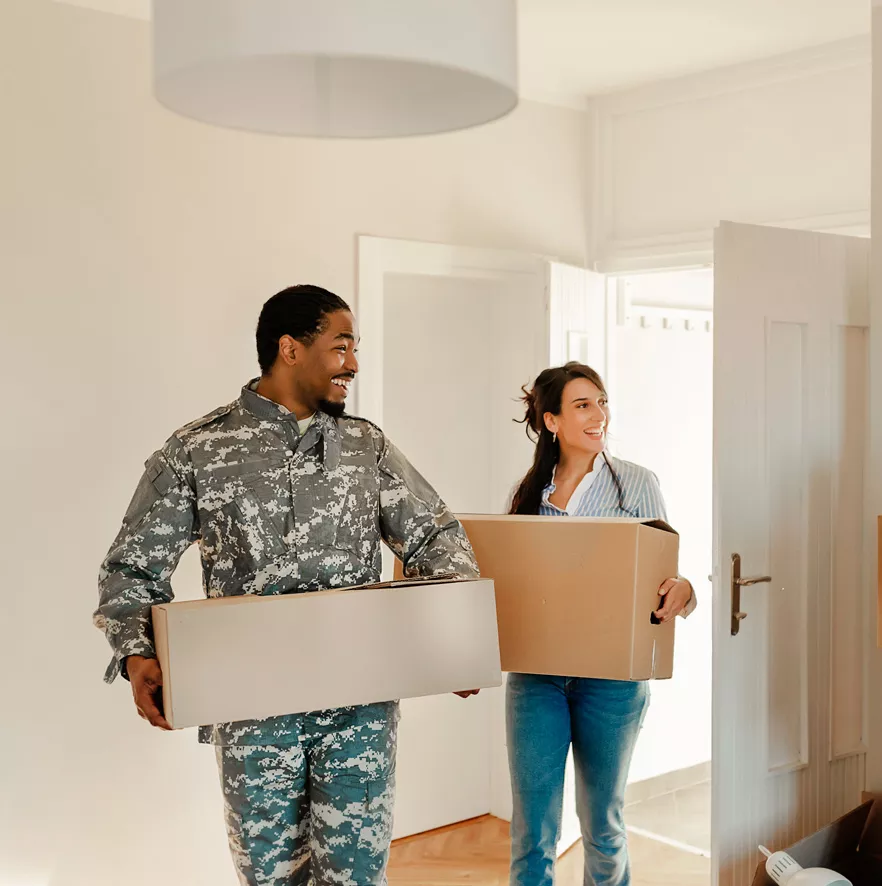 Veteran and his wife carrying boxes into their new home